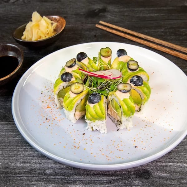 Sushi rolls with avocado, blueberries, and microgreens, served with soy sauce and pickled ginger.
