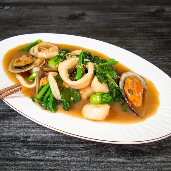 Seafood stir-fry with squid, mussels, clams, shrimp, and green vegetables in a savory sauce.